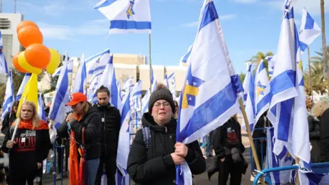 EPA People react in sorrow while holding Israeli flags at Hostages Square in Tel Aviv (20/02/25)