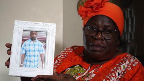 Charles Ndhlovu's mother Angelina Pattison holding a photo frame with an image of her son.