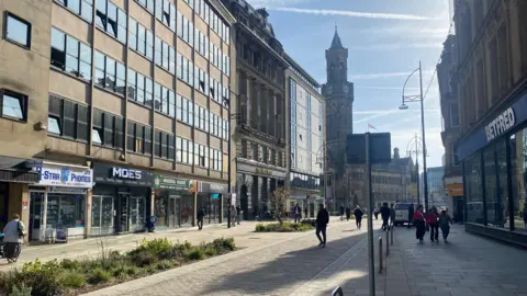 Grace Wood/BBC A quiet pedestrianised street with shops and cafes