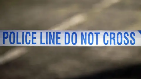 A stock image of a blue and white police tape saying: Police line, do not cross. The background of the image is blurred.