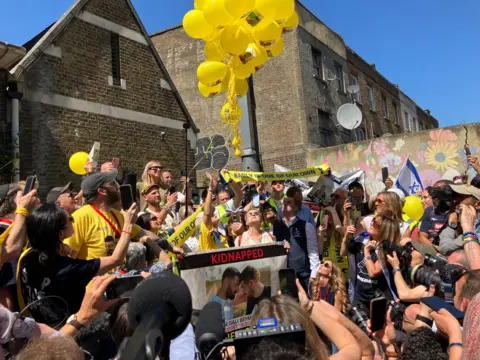 Supporters holding balloons and posters outside Tottenham Hotspur stadium