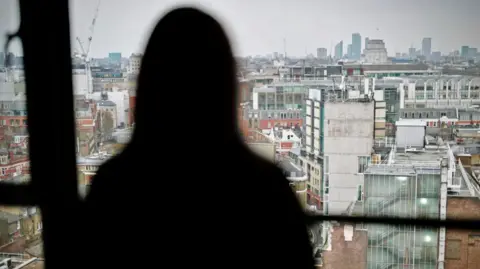 Silhouette of a woman looking over the London skyline