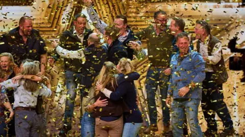 Britain's Got Talent A group of people hugging and holding their arms in the air, surrounded by gold confetti
