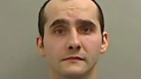 Mugshot of Milton. He is clean shaven with balding short brown hair.