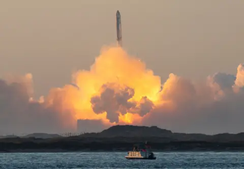 Getty Images A rocket launch along the coast, with a boat on the water in the foreground