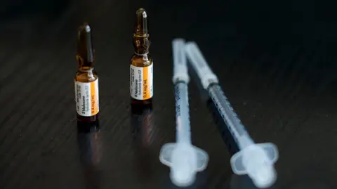 Getty Images Naxolone in small brown bottles beside two syringes on a dark wood table