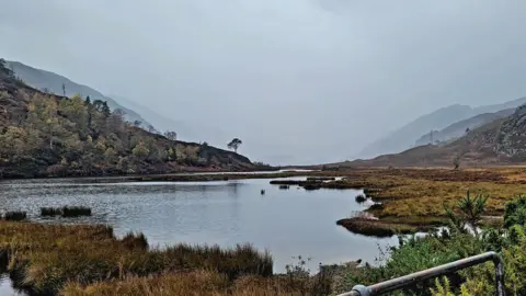 Hazel Thomson Water in the foreground with mountains on either side.