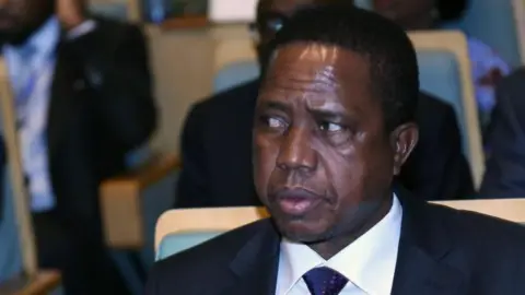 Head and shoulders shot of Edgar Lungu wearing a dark jacket, white shirt and blue tie.