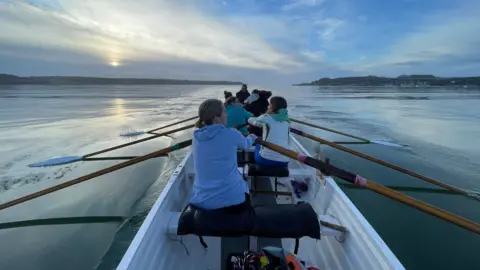 Portreath Pilot Gig Club Gig crew rowing on the water, taking from the front of the boat looking forward.