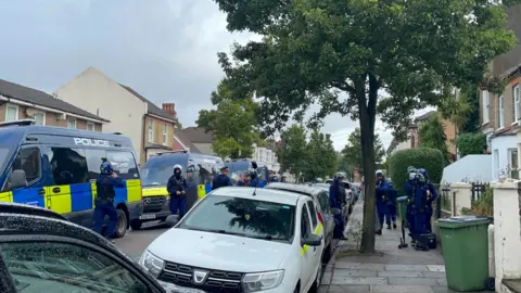 PA Media Metropolitan Police Territorial Support Group officers and vans at the scene in Eglinton Road