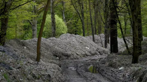 PA Media Mountains of waste piled against trees in the centre of a woodland