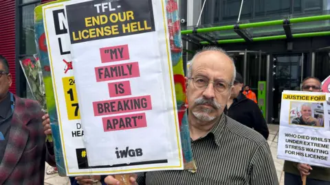 Kambiz Hemati holds up picket of Robert Dale protesting against TfL