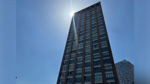Tower block with sun shining and blue sky 