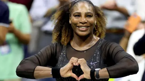 Serena Williams does a heart symbol with her hands while playing at the 2022 US Open