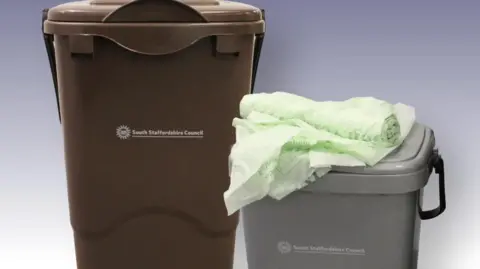 A large brown food caddy and small grey plastic one, with a roll of green bin liners resting on the top