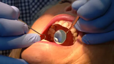 A dentist checking condition of a patient's teeth.