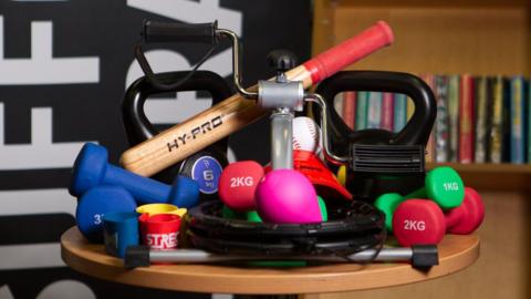 Collection of brightly coloured weights, a rounders bat and other pieces of fitness equipment  