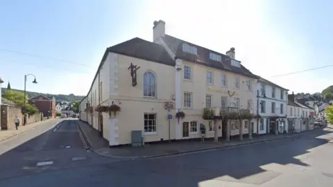 A cream coloured Georgian-style building with four floors is pictured on Okehampton high-street. The building has large oval windows and four pillars at the entrance. 