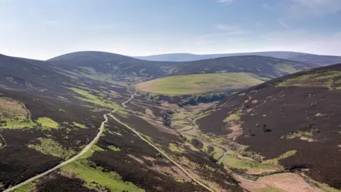 Knight Frank An aerial shot of a moorland valley with a stream slaloming through the middle of it.