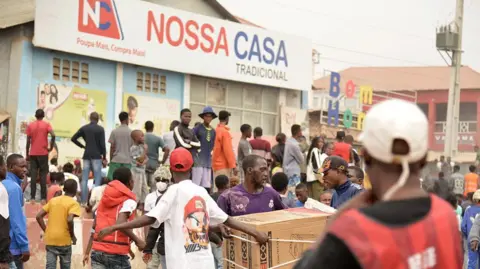 AFP via Getty Images A group of shops are targeted as looting erupted in the Kalemba 2 district of Luanda on Monday.