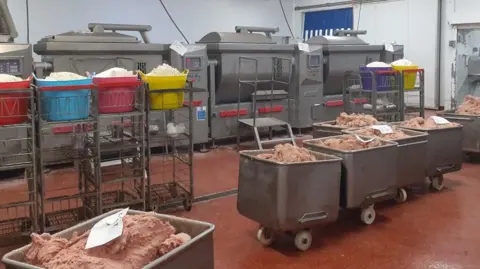 Media Wales Interior of factory with raw meat in large stainless steel containers on wheels and machines on factory floor