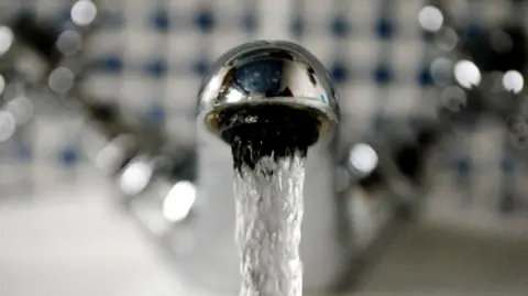 PA Media A bathroom tap with flowing water