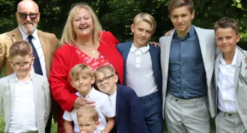 supplied A family photo with an older couple and several young smiling boys in smart suits