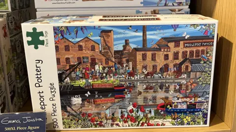 A close-up of a jigsaw box. The picture on the front depicts a drawing of Stoke-on-Trent's Middleport Pottery