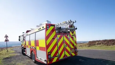 A North Yorkshire fire engine on a road over moorland