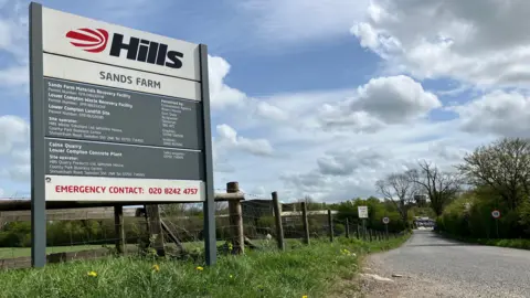 A picture of the Hills site sign on a grass verge along a country lane