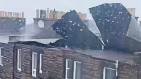 Parts of a roof fly off terraced houses in strong winds