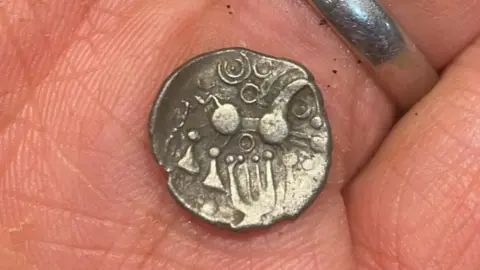 An ancient gold coin. It has simple pictures and patterns on it. 