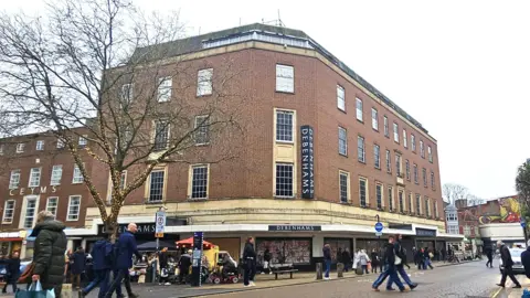 Paul Moseley/BBC A picture of the Debenhams building on a busy shopping day. The building is 5 or 6 storeys tall. A number of people are walking past it or crossing the road in front of it.