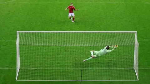 Wigan goalkeeper Tom Watson saves Kyle McAdam's penalty