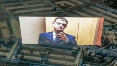 AFP An illustration shows a picture of Jack Teixeira taking a selfie while wearing a military uniform. The picture is superimposed on the US Pentagon building.