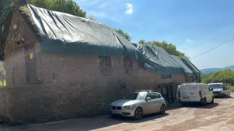 The exterior of the Blue Ball pub with a cover over the thatched roof