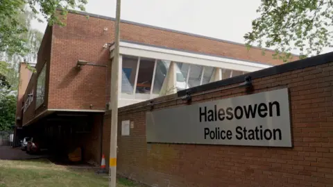 Exterior of Halesowen police station, a red-brick building with large white window along one side