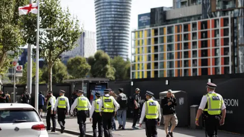 EPA A group of police officers walking along a street, wearing hi-vis