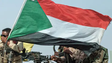 AFP/Getty Images A Sudanese flag flying on a vehicle (not seen) mounted by a gun manned by RSF soldiers.