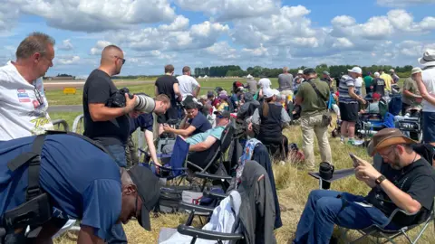 Crowds of plane enthusiasts, many with long lens cameras gathered on the edge of the runway at RAF Fairford