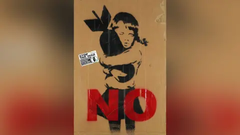 A Banksy placard showing a child hugging a bomb with the word "No" in red writing across the bottom.