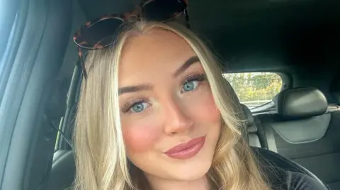 Lily-May Edwards A selfie of Lily-May without her glasses. She wear dark sunglasses on top of her head. She has blue eyes and pink lipstick