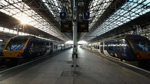 Two trains parked at a platform at Manchester Piccadilly station.