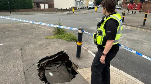 Cambridgeshire Police police officer standing inside the cordon - next to the sinkhole
