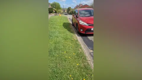 Ozzy O'Shea Yellow lines on a village road obscured with black paint and a car parked on them