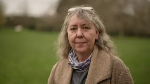 Woman with grey hair and glasses on her hair smiles at the camera