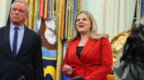 Heidi Overton, wearing red, speaking in the Oval Office beside health secretary Kennedy