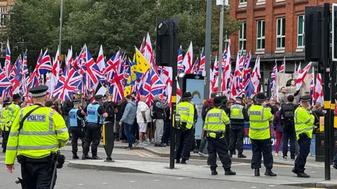 British flags being waved by Britain First members as they march through Birmingham. About 10 police officers in high-vis clothing are also there 