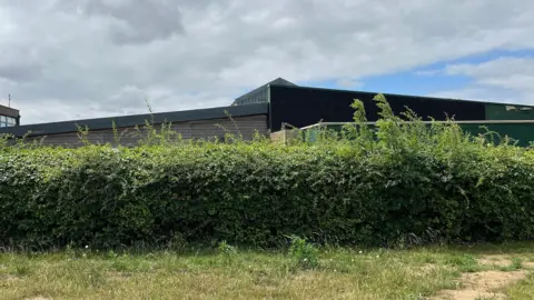 View of the English and Technology block at Reepham high. A building is part covered in black material which is sound proofing applied to try and reduce the noise from an air source heat pump.