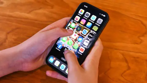 Young person's hand holding a mobile phone